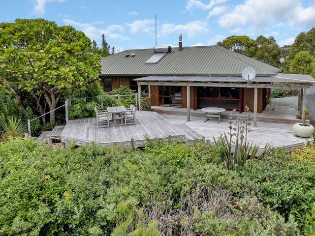A house with a deck and dining area at Matapouri Holiday Home in Whangarei