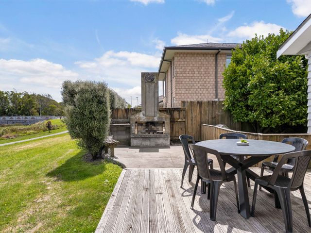 An outdoor garden with a table and chairs near a barbecue at Sunlit Shores - Papamoa Holiday Homes