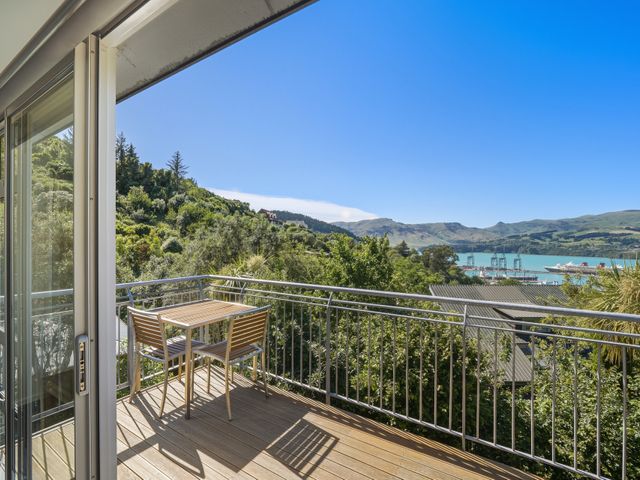 An outdoor balcony with a table and chairs overlooking a water view at Lyttelton Holiday Home in Lyttelton