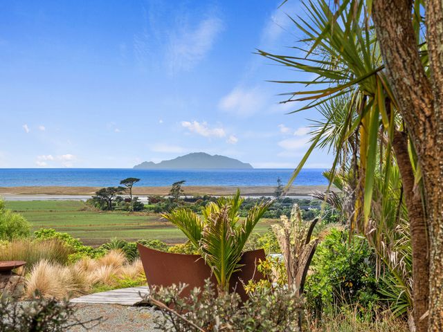 A garden view with plants and ocean at Black Dune in Waipu