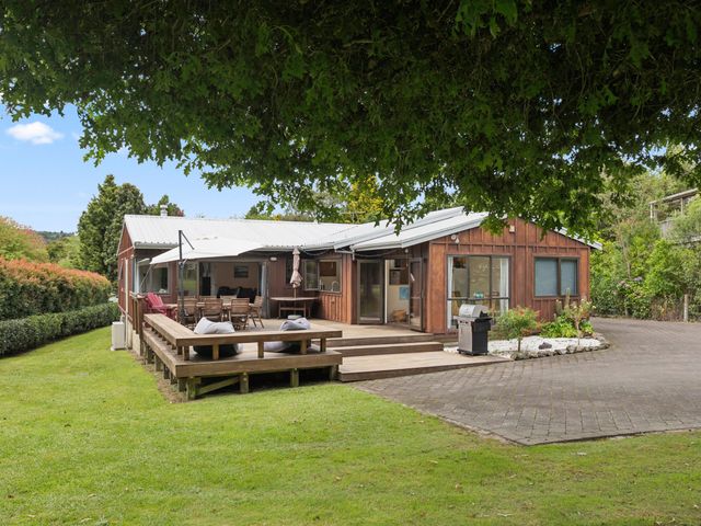 An exterior view of a house with a deck and dining area at Paradise At 471 - Rotorua Holiday Home in Rotorua