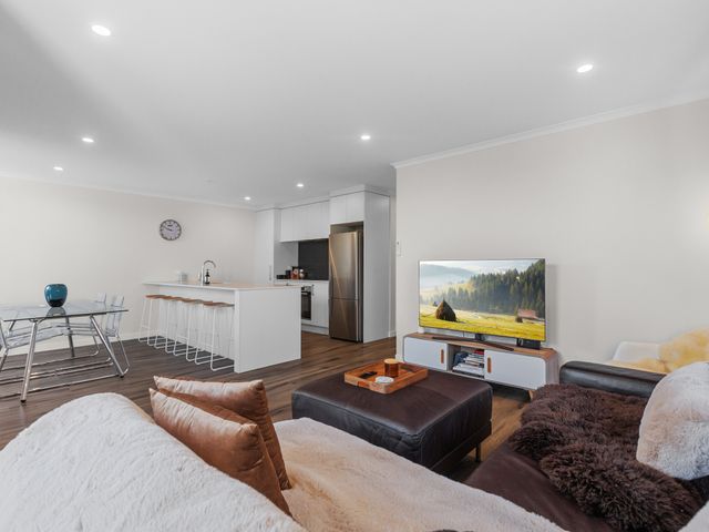 A living room with a kitchen island and bar stools at Papamoa