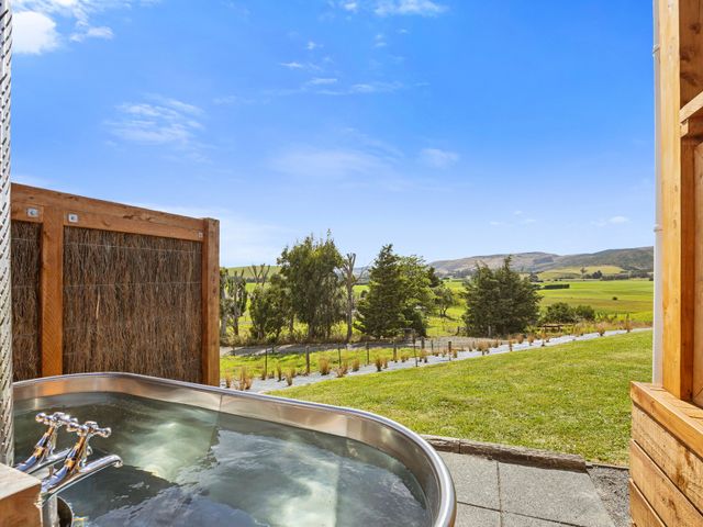 An outdoor hot tub overlooking a grassy field and trees at Limesprings Cottage - Milton