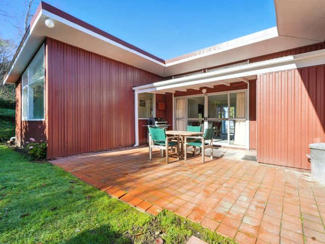 A patio with table and chairs at Maison Pierre Rouge - Duvauchelle Holiday Home Akaroa