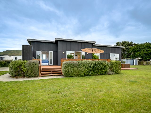 A house with a deck and an umbrella at SeaRenity - Waimarama Holiday Home Waimarama
