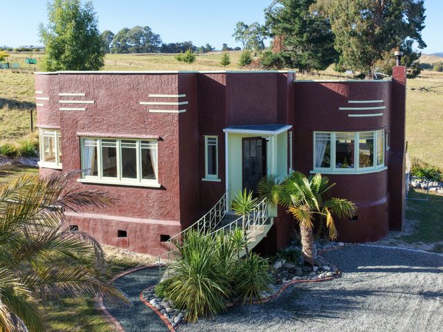 A house with windows and palm trees at Kettle House - Upper Moutere Holiday Home