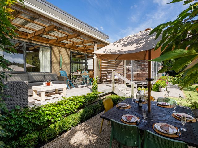 An outdoor area with a sofa, table, and dining set at River Cottage - Whitianga Holiday Home