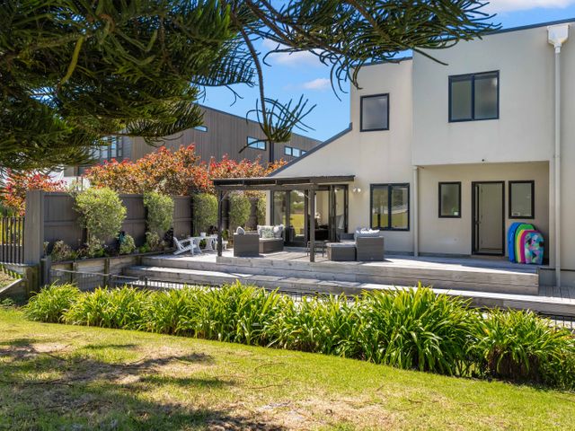 A house with a deck and outdoor furniture at Mount Maunganui