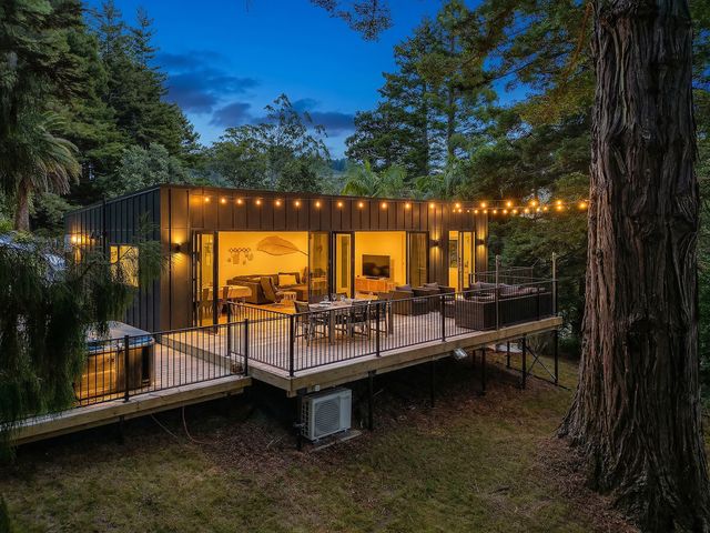An outdoor area with a deck, table and chairs at Modern Coastal Tree House - Whangamata