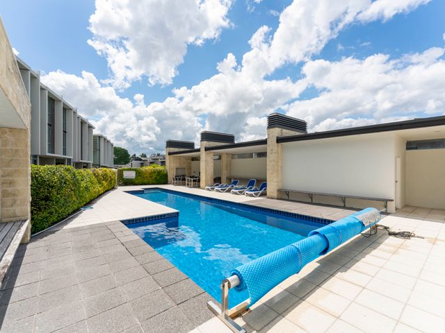An outdoor area with a swimming pool and poolside chairs at Lake Taupo Holiday Home in Taupo