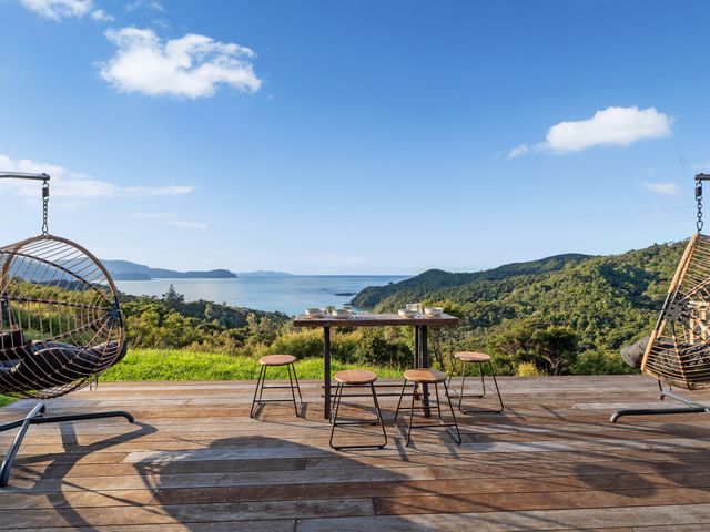 A dining area with hanging chairs and a view of the ocean at Little Tui Ridge - Coromandel Holiday Home Coromandel