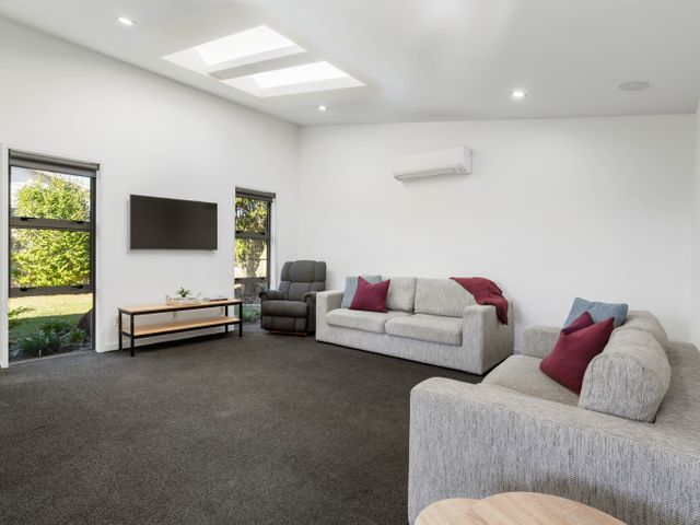 A living room with couches and a television at Sun & Surf Stay - Papamoa Holiday Home