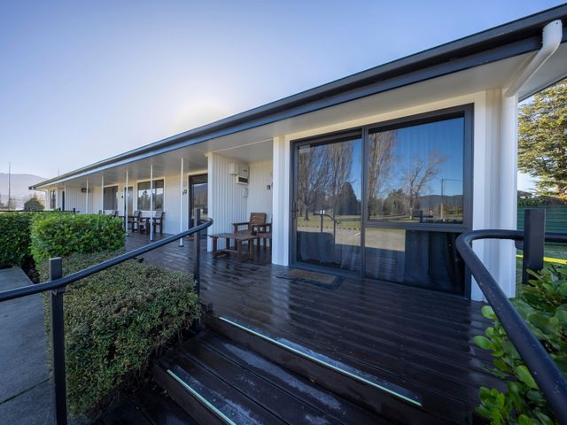 An outdoor area with a porch and chairs at Mustering - Te Anau Holiday Home in Te Anau