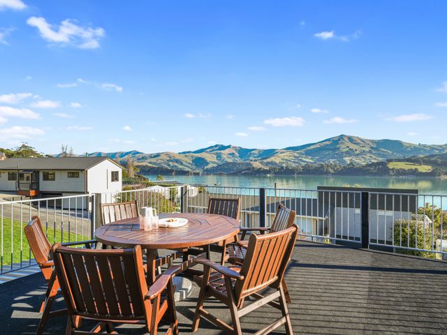 An outdoor seating area with table and chairs overlooking a lake at Belle Vue Akaroa