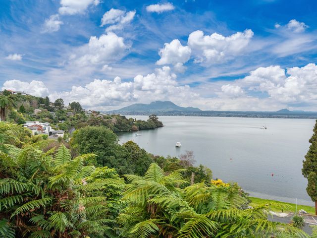 A view of a lake with surrounding trees and mountains at Serenity Above the Lake - Acacia Bay Holiday Home
