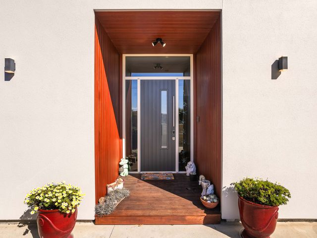 An entryway with a front door and flower pots at Ohana - Papamoa Holiday Home