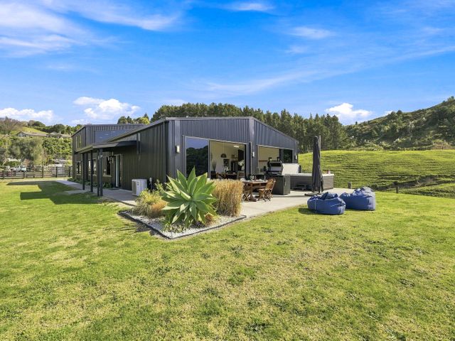 An outdoor seating area with a house in a garden at The Black Barn - Whakatane Holiday Home