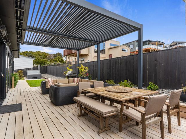 An outdoor seating area with a dining table and chairs at Langs Life - Waipu Holiday Home Waipu Cove