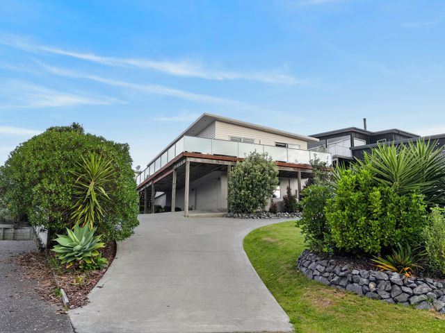 A house with a balcony and driveway at Sunset Vista - Mangawhai Heads