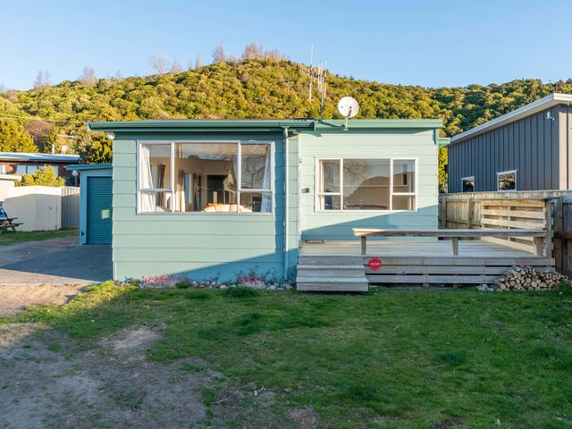 A house with a deck and garage at Motuoapa Holiday Home in Motuoapa