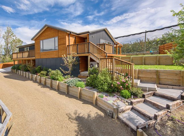 Exterior of a wooden house with stairs and raised garden beds with plants at Pisa View Paradise in Cromwell