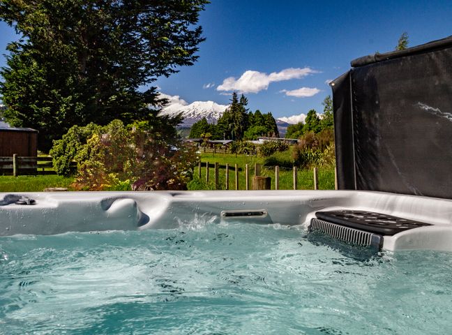 Water in a hot tub with trees and a snow capped mountain in the background at Bluebird on Snowmass - Ohakune Holiday Home Ohakune