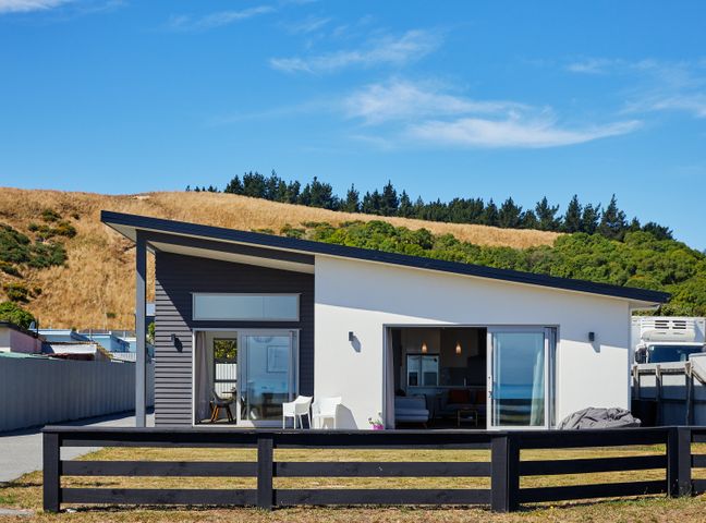 A modern single story house with a slanted roof and large sliding glass doors at The Kaikoura Bach Retreat in Kaikoura