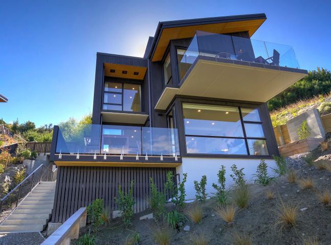 A modern house with large glass windows and balconies on a slope at The Villa Lookout - Queenstown Holiday Villa in Queenstown