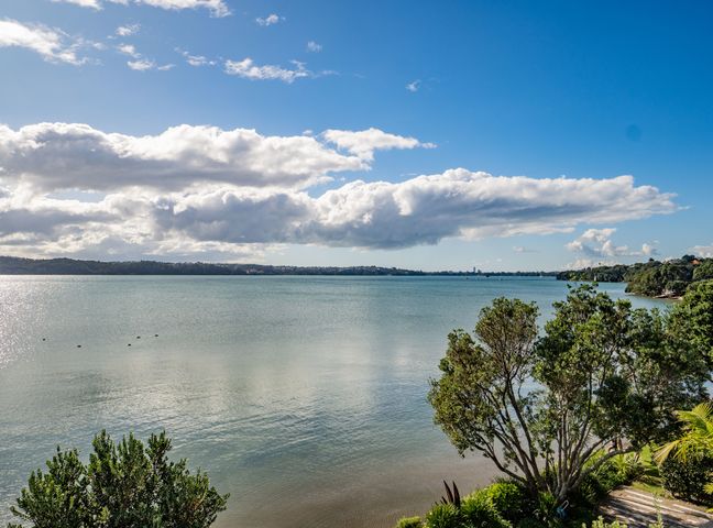 A waterfront view with water trees and clouds at Harbour View - Westmere Holiday Apartment in Auckland