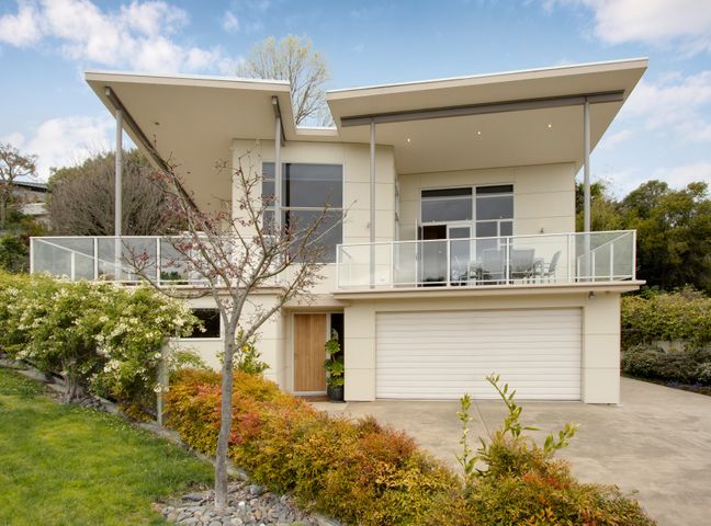 A modern two-story house with balcony and garage surrounded by plants and trees at Havelock Wine Down - Havelock North Holiday Home