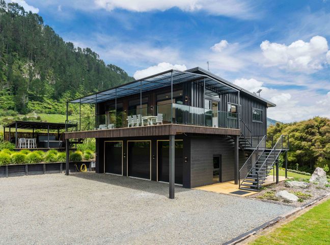A modern two-story house with an upper deck and stairs surrounded by greenery at Lakeview Oasis - Lake Whakamaru Retreat in Waikato