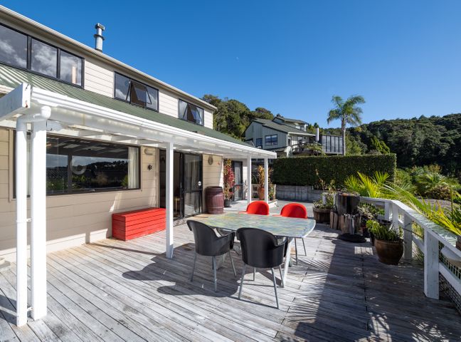 An outdoor wooden deck with a table and four chairs near a house surrounded by plants at Kings Summer House - Paihia Holiday Home in Paihia
