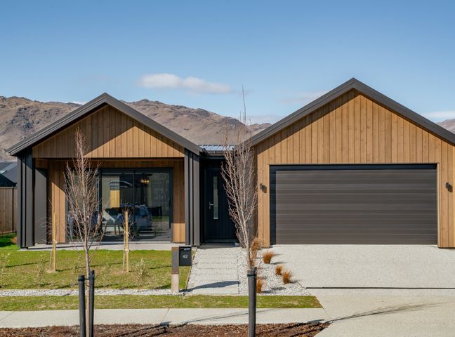 A modern single-story house with wooden siding a double garage and young trees in front yard at Wooing Tree Beauty Cromwell