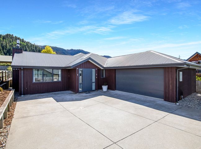 A single story house with a large driveway and a double garage at Happy Hanmer - Hanmer Springs Holiday Home in Hanmer Springs