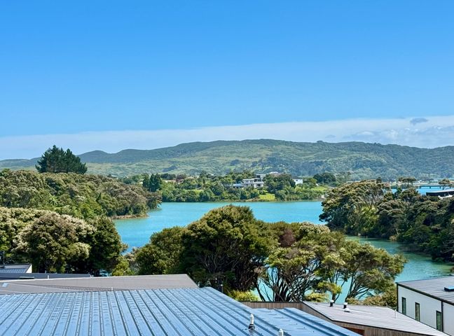 A view of water surrounded by hills and trees at Sunset Stay - Raglan Holiday Home, Raglan