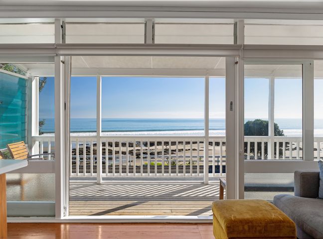 A living room with a view of the ocean and beach at Ahipara in Kaitaia