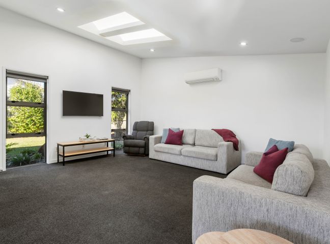 A living room with couches and a television at Sun & Surf Stay - Papamoa Holiday Home