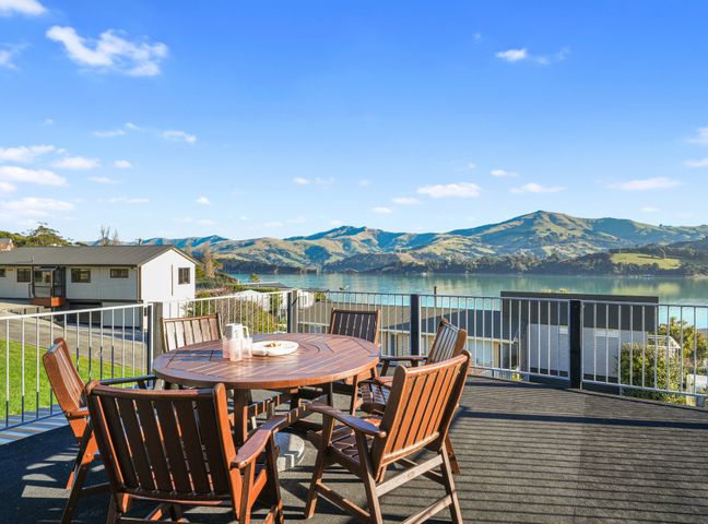 An outdoor seating area with table and chairs overlooking a lake at Belle Vue Akaroa