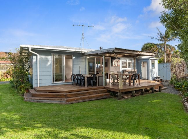 A house with a deck and outdoor seating at Coastal Hideaway - Waipu Cove Holiday Home in Waipu