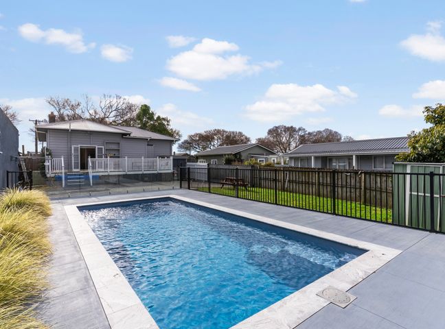 A swimming pool with a fence and a house in Auckland Holiday Home, Auckland