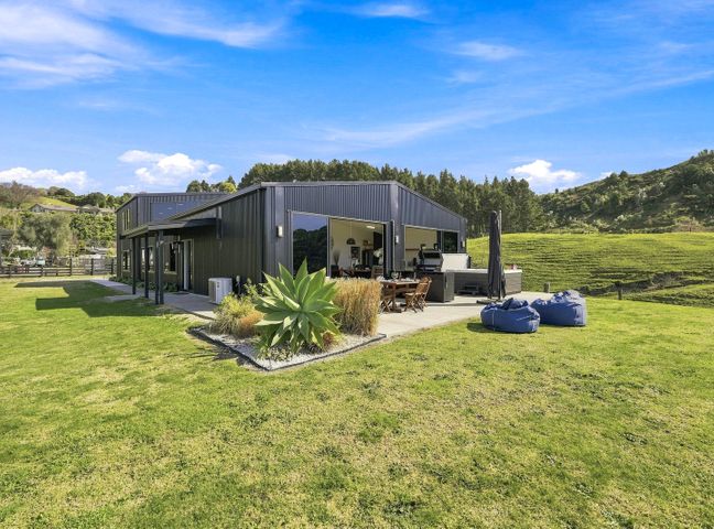 An outdoor seating area with a house in a garden at The Black Barn - Whakatane Holiday Home