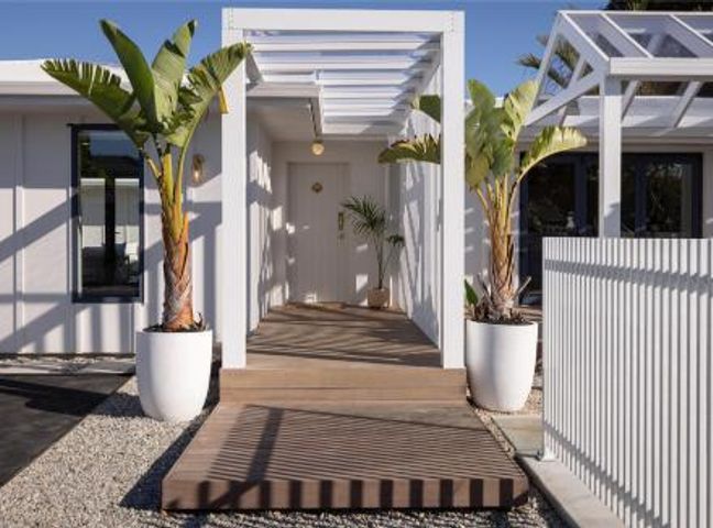 A front entrance with palm trees and a wooden walkway at Poolside on Moffat - Tauranga