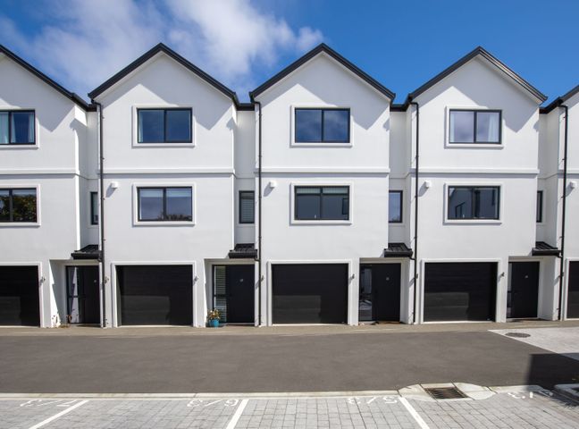 A row of townhouses with garage doors and a parking lot at Town house by Hàgley Park - Christchurch