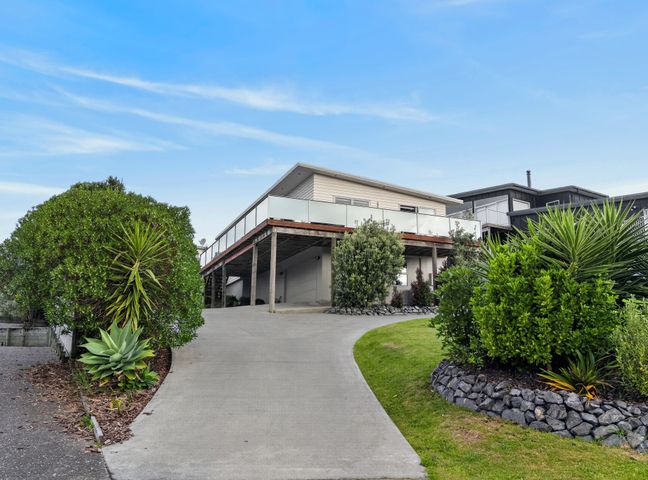 A house with a balcony and driveway at Sunset Vista - Mangawhai Heads