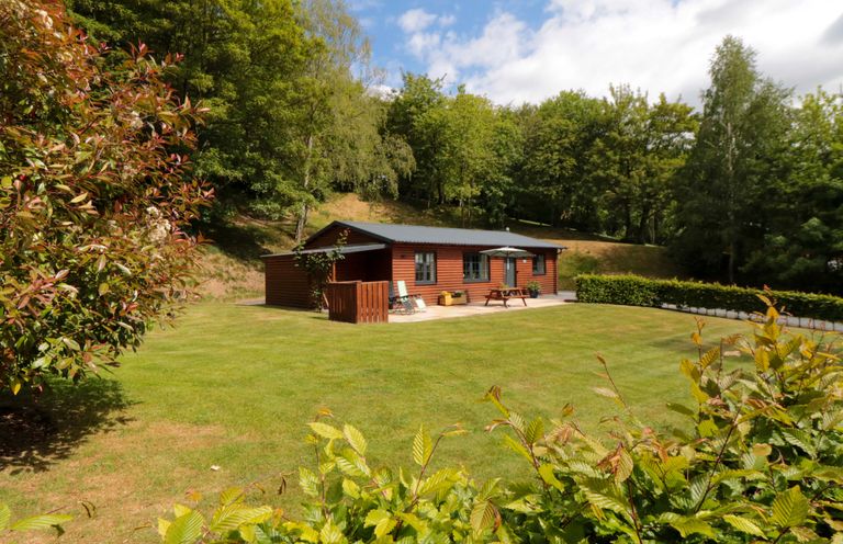 An outdoor garden with a lodge and seating at Ryedale Country Lodges - Willow Lodge in Kirkbymoorside