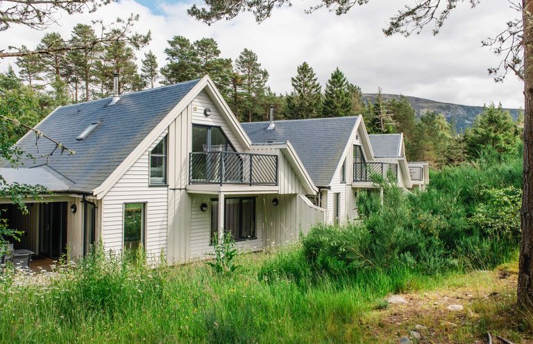 A row of houses with balconies surrounded by trees and grass at Otter Lodge in Feshiebridge near Aviemore