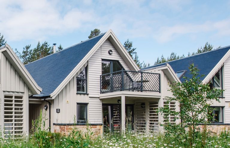 A modern two-story house with a balcony surrounded by wildflowers at Red Deer Lodge in Feshiebridge near Aviemore
