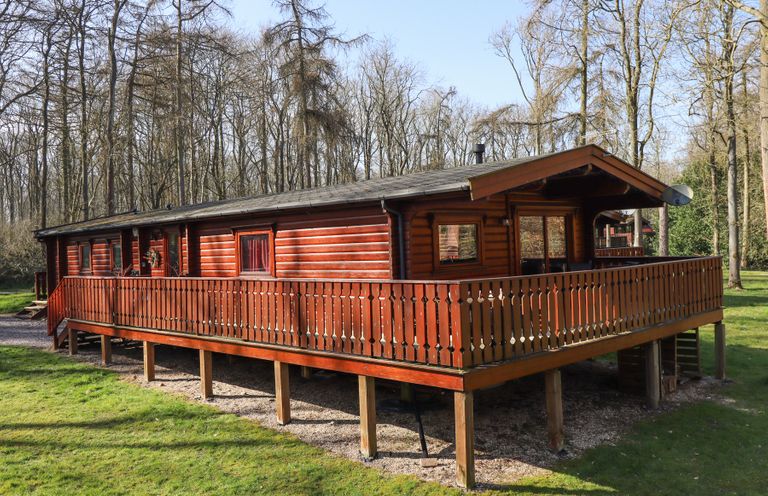 A wooden cabin with a wraparound porch surrounded by trees at Great Leap in Louth