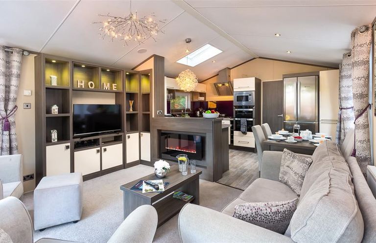A living room with a television fireplace and dining table at Lancashire Rose in Ambleside