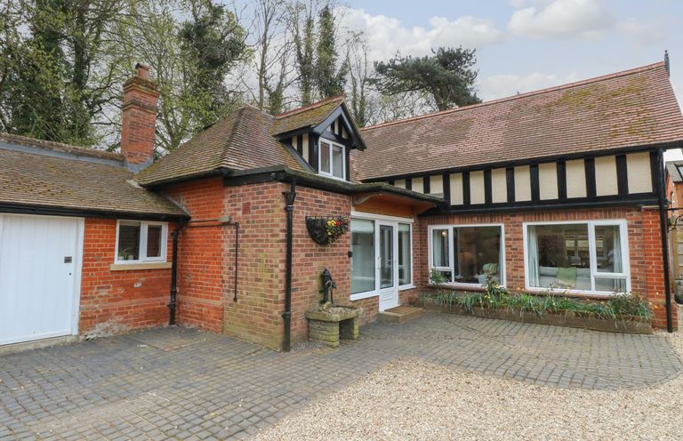 Exterior of a brick and timber house with cobblestone and gravel driveway at The Lodge in Wroxham